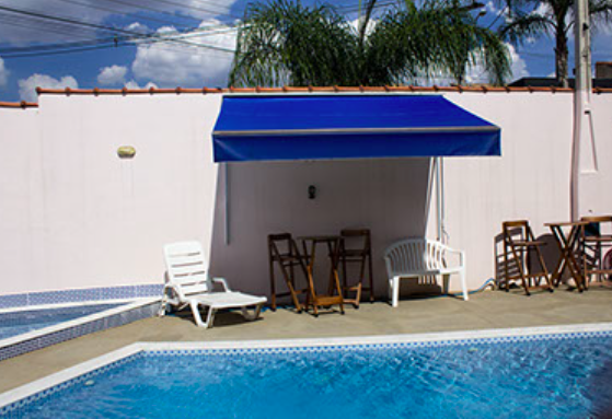 Área da piscina com toldo azul e espreguiçadeira