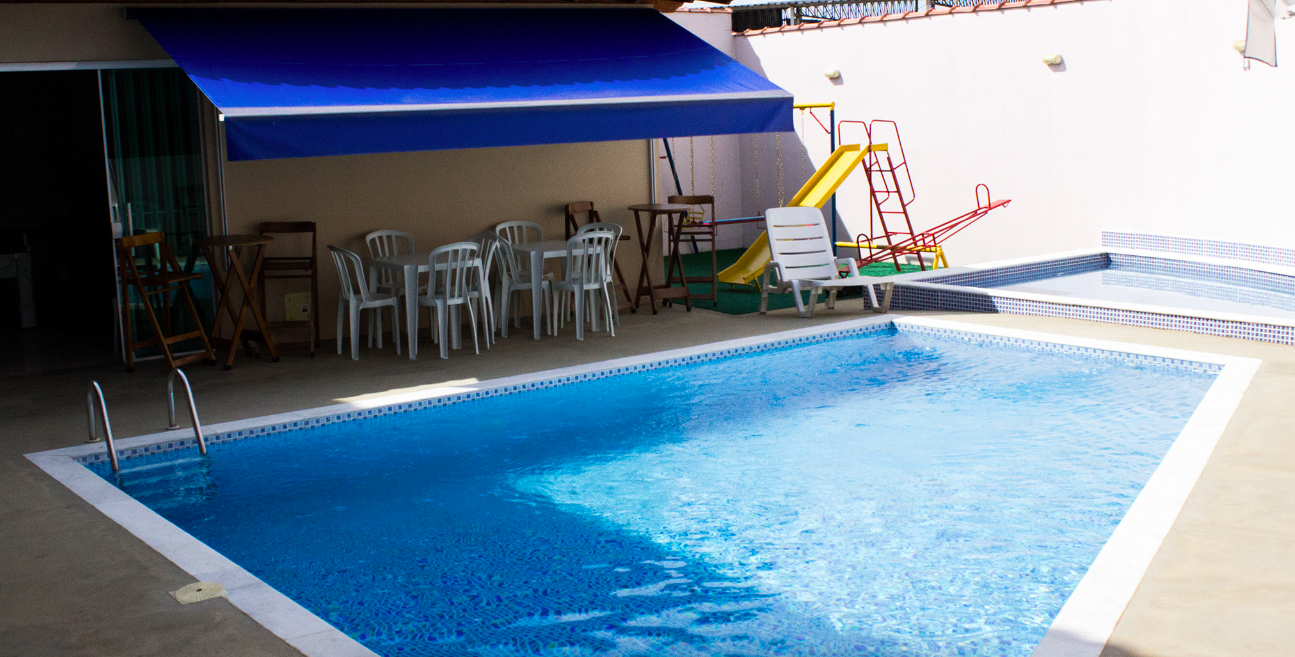 Área de lazer do Espaço Wannel com piscina, mesas, toldo e playground